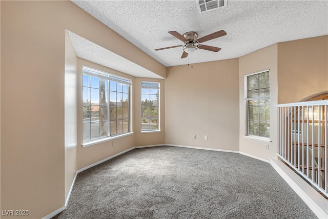 carpeted empty room featuring visible vents, a textured ceiling, baseboards, and a ceiling fan