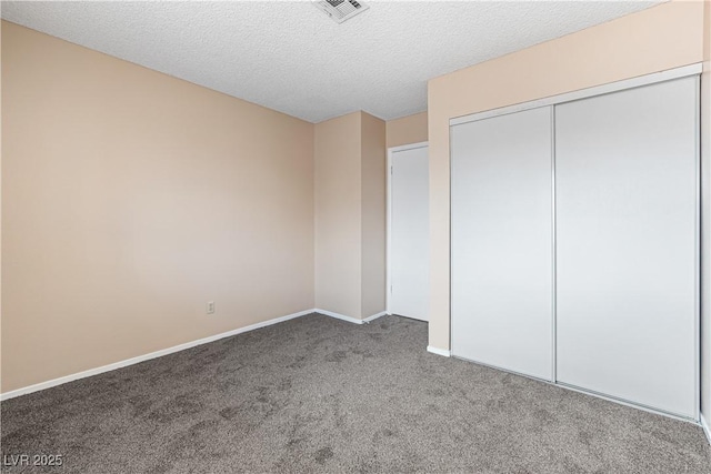 unfurnished bedroom featuring baseboards, visible vents, carpet floors, a closet, and a textured ceiling