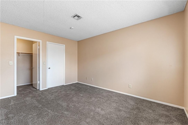 unfurnished bedroom featuring baseboards, visible vents, dark carpet, and a textured ceiling