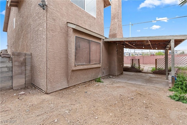 view of side of property with stucco siding and fence