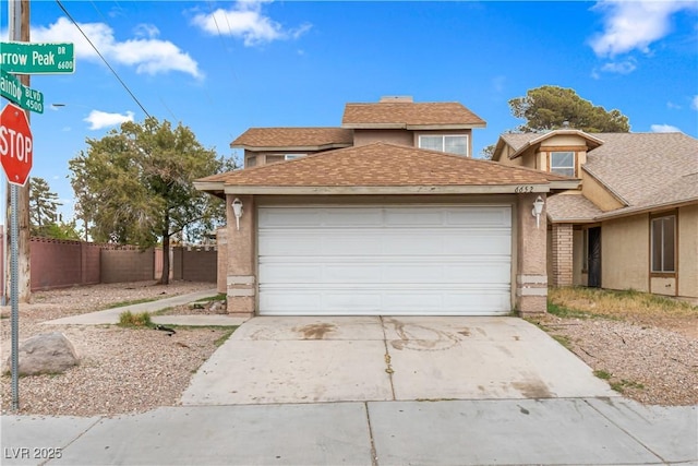 view of front of home with a shingled roof, concrete driveway, a garage, and fence