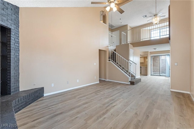 unfurnished living room with a fireplace, stairway, and a ceiling fan