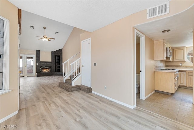 unfurnished living room with stairs, visible vents, light wood-type flooring, and a ceiling fan