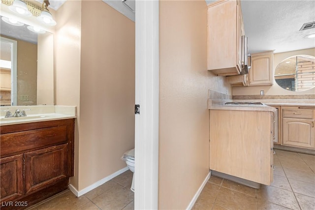 kitchen with visible vents, light brown cabinetry, a sink, light countertops, and light tile patterned floors