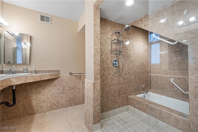 bathroom featuring visible vents, a sink, tiled shower / bath combo, tile patterned floors, and tile walls