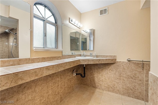 bathroom featuring a sink, visible vents, tiled shower, and tile patterned flooring