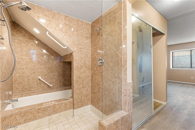 full bath with a tile shower, baseboards, a textured ceiling, and a relaxing tiled tub