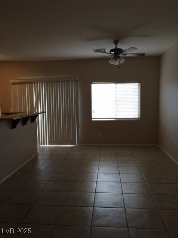 unfurnished room with baseboards, dark tile patterned floors, and a ceiling fan