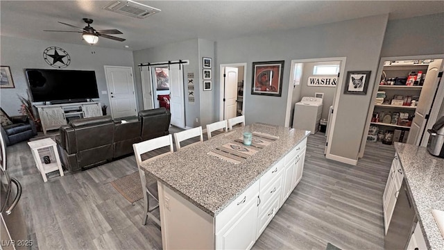 kitchen with visible vents, ceiling fan, a breakfast bar area, washer / dryer, and light wood-style floors