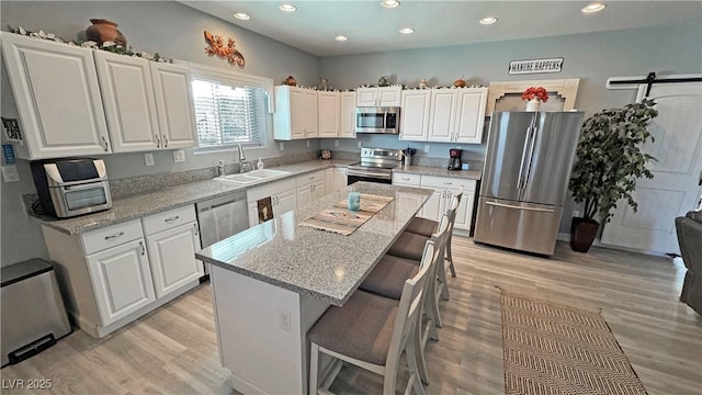 kitchen featuring white cabinets, stainless steel appliances, light wood-type flooring, and a sink