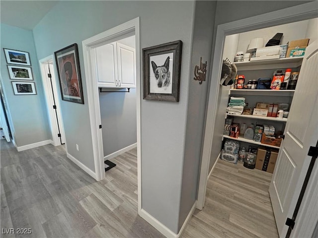 hallway featuring light wood finished floors and baseboards