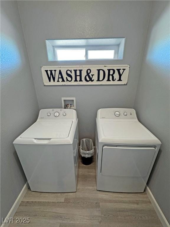 laundry area featuring light wood-style flooring, separate washer and dryer, and baseboards