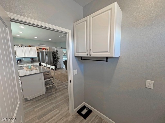 laundry room with baseboards, light wood-type flooring, a barn door, laundry area, and recessed lighting