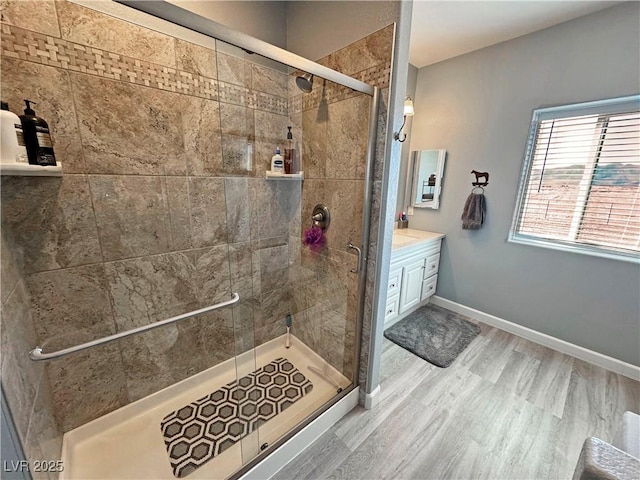 bathroom featuring a shower stall, vanity, baseboards, and wood finished floors