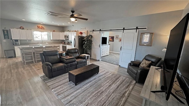 living room featuring visible vents, recessed lighting, a barn door, light wood-style floors, and ceiling fan