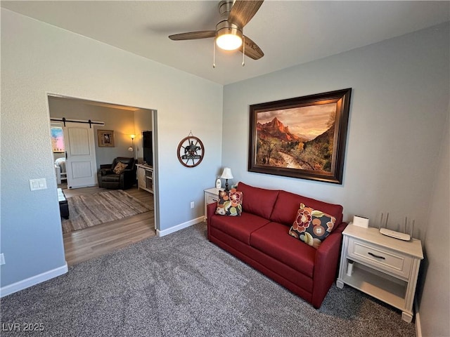 carpeted living room featuring a barn door, baseboards, and a ceiling fan