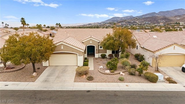 view of front facade with stucco siding, a tile roof, a mountain view, concrete driveway, and a garage