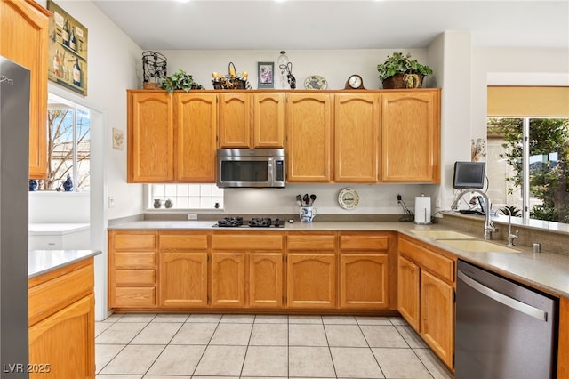 kitchen with light tile patterned floors, stainless steel appliances, light countertops, and a sink