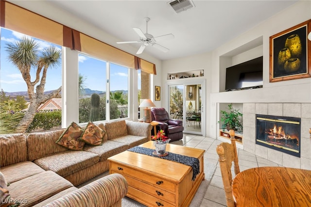 sunroom with visible vents, ceiling fan, and a tile fireplace