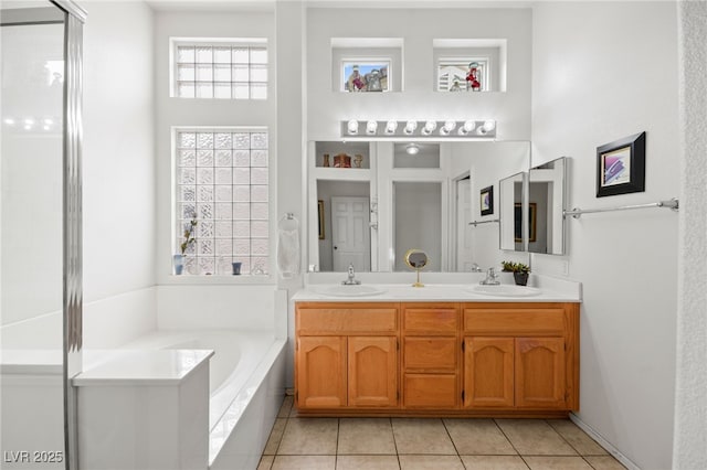 bathroom with a garden tub, double vanity, tile patterned floors, and a sink