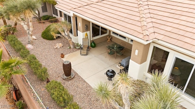 exterior space featuring a patio area, stucco siding, a tile roof, and fence