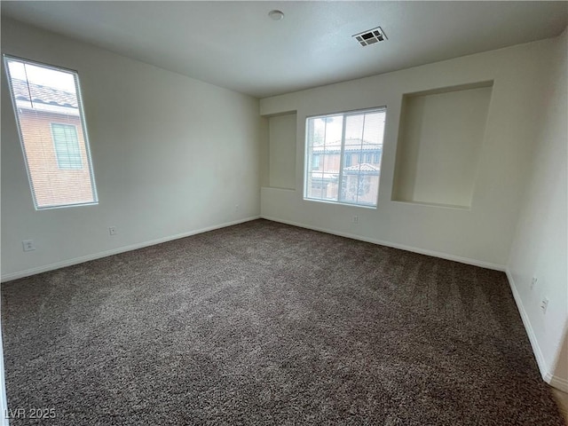 carpeted empty room featuring baseboards and visible vents