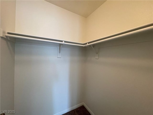 walk in closet with dark carpet