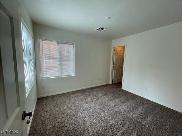 carpeted empty room featuring a wealth of natural light, visible vents, and baseboards