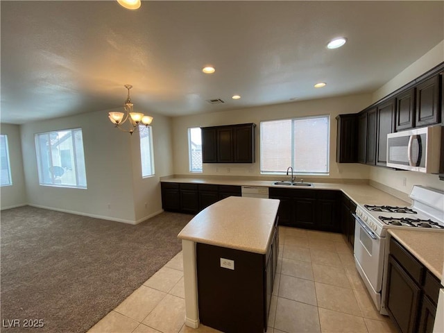 kitchen with stainless steel microwave, visible vents, white gas range oven, light carpet, and a sink