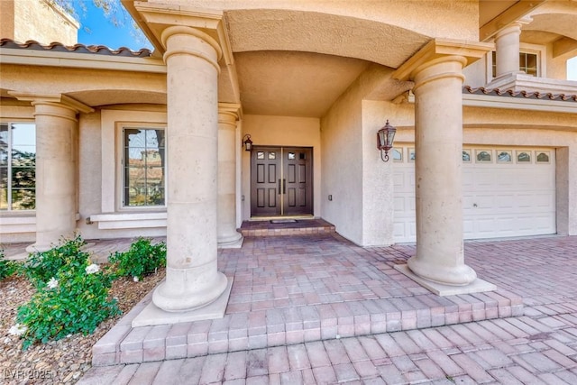 view of exterior entry with decorative driveway and an attached garage