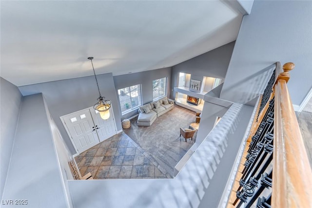 living room featuring stone finish flooring, baseboards, lofted ceiling, and a glass covered fireplace