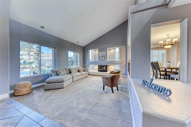 tiled living room with baseboards, a chandelier, carpet floors, a glass covered fireplace, and high vaulted ceiling