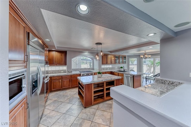 kitchen with a center island, built in appliances, a peninsula, brown cabinetry, and a sink