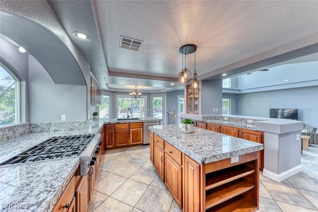 kitchen with visible vents, a peninsula, a sink, appliances with stainless steel finishes, and a center island