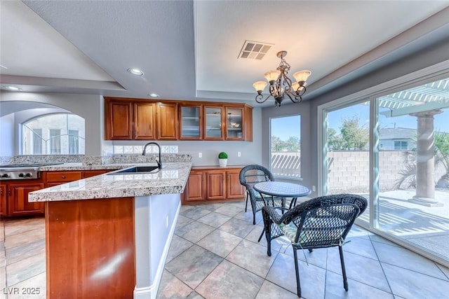 kitchen with visible vents, brown cabinets, a peninsula, a raised ceiling, and stainless steel gas cooktop