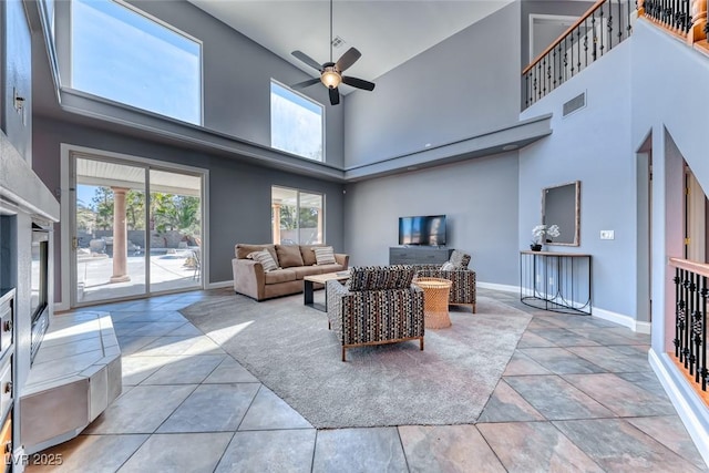 living room with visible vents, baseboards, a high ceiling, and a ceiling fan