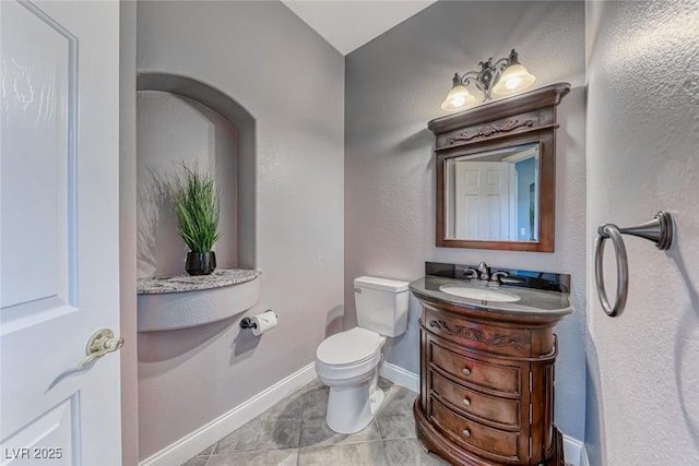 bathroom featuring vanity, toilet, baseboards, and tile patterned flooring