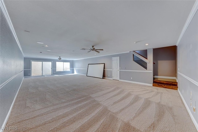 unfurnished living room featuring a ceiling fan, baseboards, carpet floors, and ornamental molding