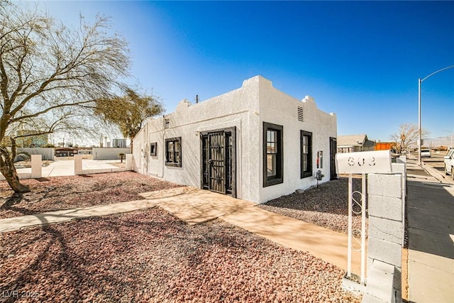 view of front of home featuring stucco siding, a patio, and fence