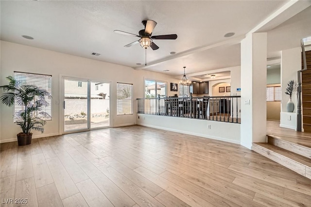 unfurnished living room featuring visible vents, ceiling fan with notable chandelier, light wood-type flooring, and baseboards