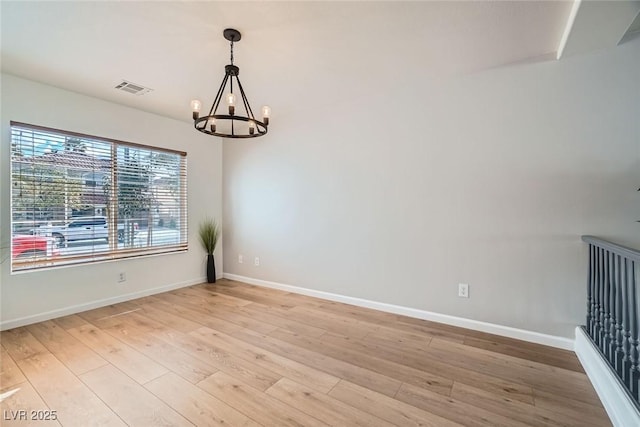 unfurnished room with a chandelier, visible vents, baseboards, and light wood-style floors