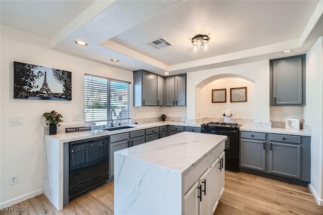 kitchen with visible vents, gray cabinetry, arched walkways, black appliances, and a raised ceiling