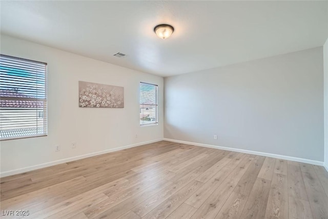 empty room featuring visible vents, baseboards, and light wood-style floors