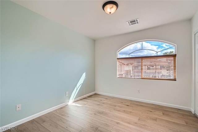 spare room with visible vents, baseboards, and wood finished floors