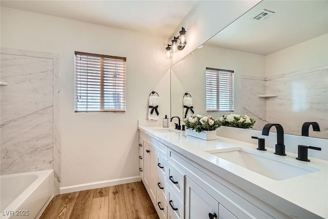 bathroom featuring double vanity, wood finished floors, visible vents, and a sink