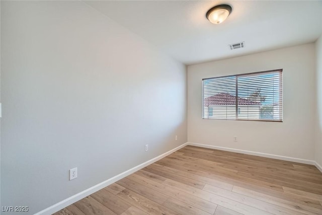 unfurnished room featuring light wood finished floors, visible vents, and baseboards