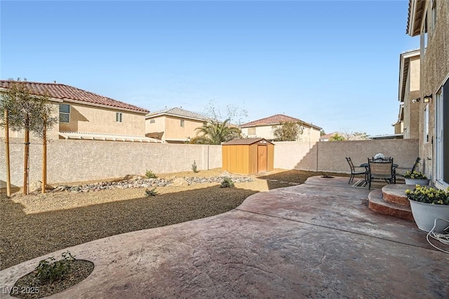 view of patio / terrace featuring an outbuilding, a fenced backyard, and a shed