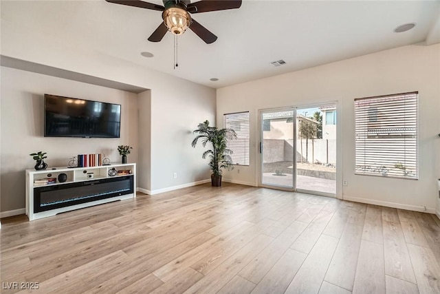 living room featuring a ceiling fan, visible vents, wood finished floors, and baseboards