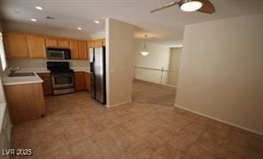 kitchen with a ceiling fan, a sink, freestanding refrigerator, black microwave, and gas range