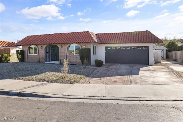 mediterranean / spanish-style house with fence, stucco siding, concrete driveway, a garage, and a tiled roof